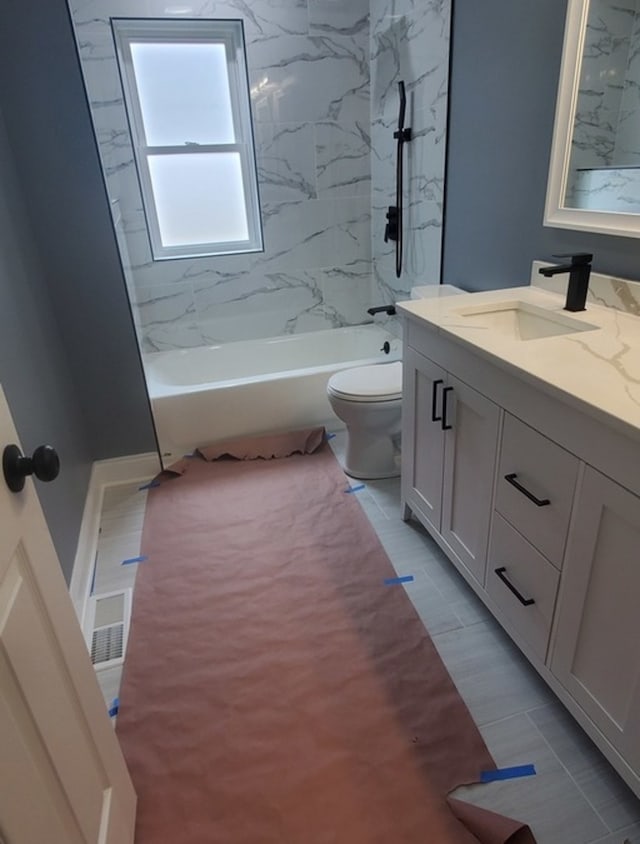 full bathroom with tiled shower / bath, vanity, toilet, and tile patterned floors