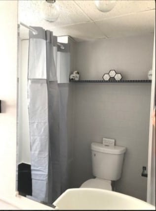 bathroom featuring a drop ceiling, toilet, and tile walls