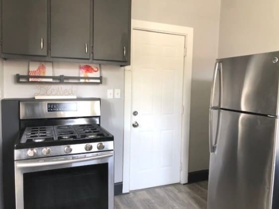 kitchen with appliances with stainless steel finishes, wood-type flooring, and dark brown cabinetry