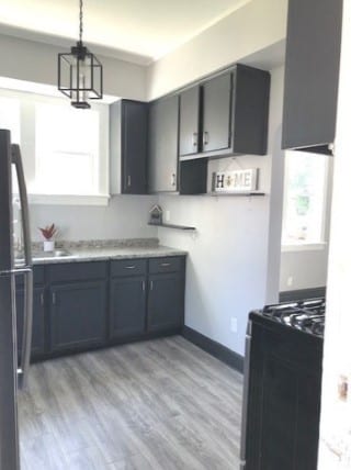 kitchen with decorative light fixtures, a chandelier, black refrigerator, range, and light wood-type flooring