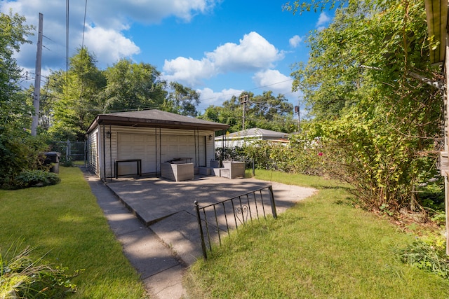 view of yard featuring a garage, a patio area, and an outbuilding