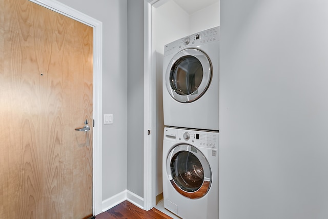 clothes washing area featuring stacked washer and clothes dryer and dark hardwood / wood-style floors