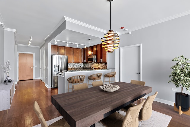 dining space featuring rail lighting, dark wood-type flooring, and ornamental molding