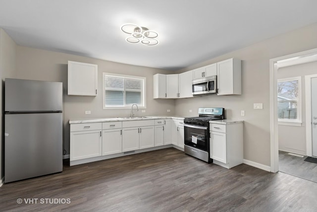 kitchen featuring appliances with stainless steel finishes, sink, white cabinets, and dark hardwood / wood-style flooring