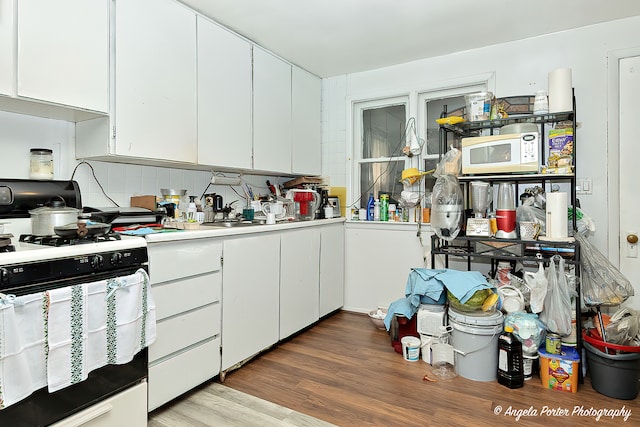 kitchen with white cabinetry, hardwood / wood-style floors, decorative backsplash, and white appliances