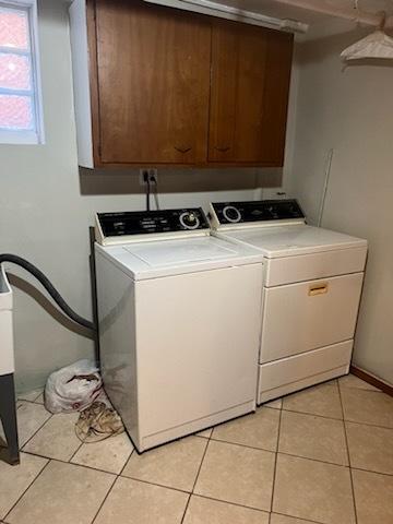 clothes washing area with independent washer and dryer, cabinet space, and light tile patterned flooring