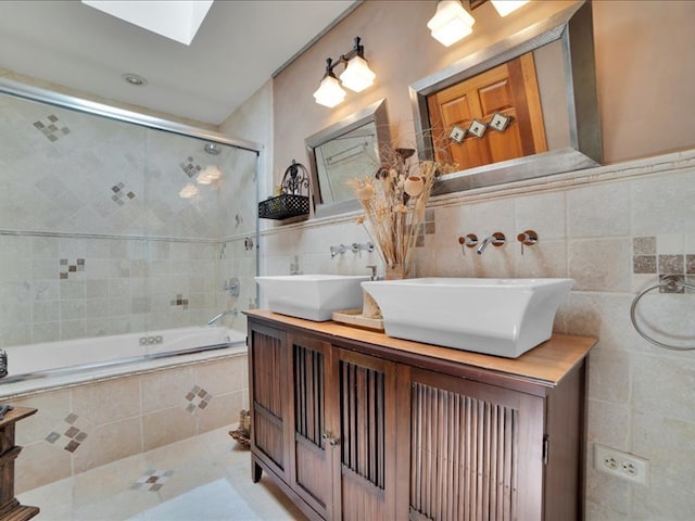 bathroom featuring combined bath / shower with glass door, tile patterned flooring, double vanity, a skylight, and tile walls