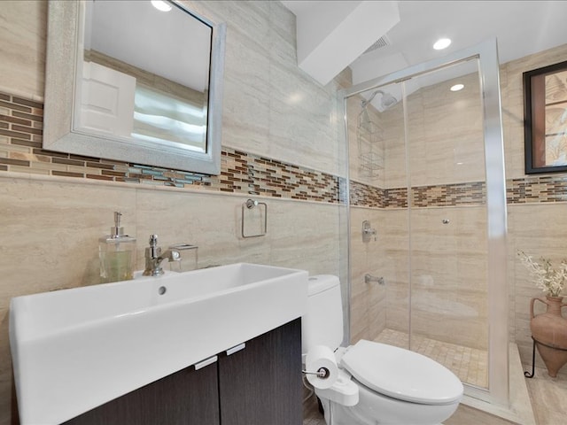 bathroom featuring a shower with door, toilet, tasteful backsplash, tile walls, and sink