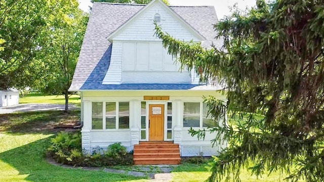 view of front facade featuring entry steps, a shingled roof, and a front lawn