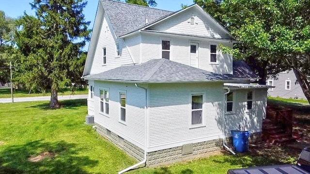 view of property exterior featuring a shingled roof and a yard