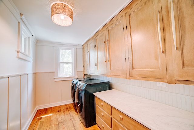 washroom with light wood-type flooring, cabinets, and washing machine and dryer