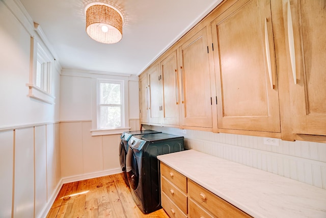 laundry area with cabinet space, light wood-style flooring, wainscoting, separate washer and dryer, and baseboards