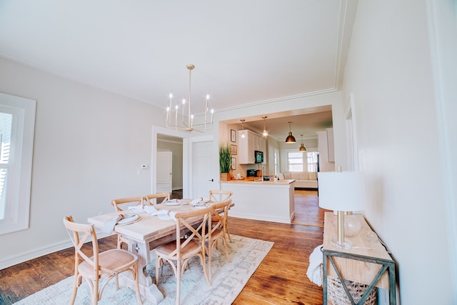 dining space featuring ornamental molding, a chandelier, and wood-type flooring