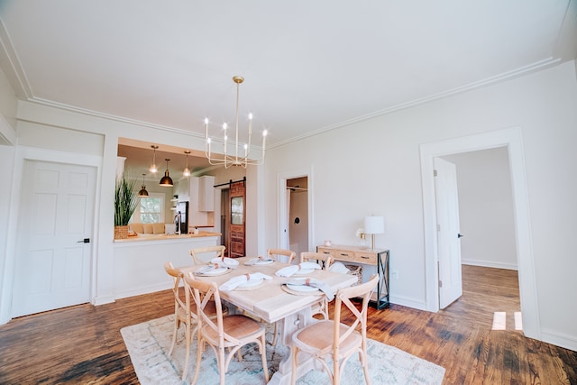 dining room featuring hardwood / wood-style floors, a barn door, ornamental molding, and a chandelier