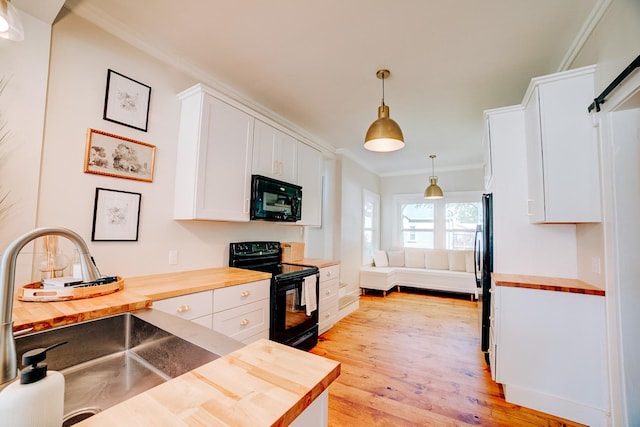 kitchen featuring black appliances, butcher block countertops, decorative light fixtures, and white cabinets