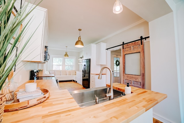 kitchen with sink, black fridge with ice dispenser, range, a barn door, and white cabinets