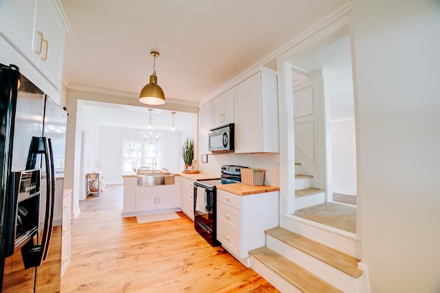 kitchen with light wood-type flooring, butcher block countertops, white cabinets, black / electric stove, and stainless steel fridge