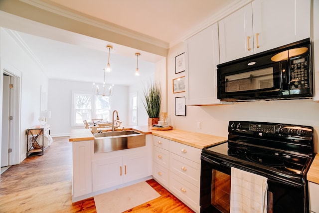 kitchen featuring a sink, white cabinets, hanging light fixtures, black appliances, and crown molding