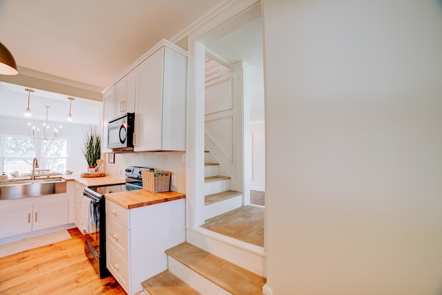 kitchen featuring butcher block counters, sink, electric stove, light wood-type flooring, and white cabinets