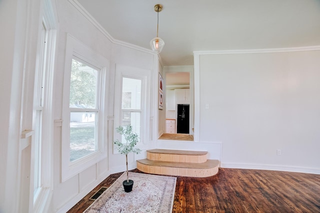 entrance foyer with a wealth of natural light, visible vents, dark wood-style flooring, and crown molding