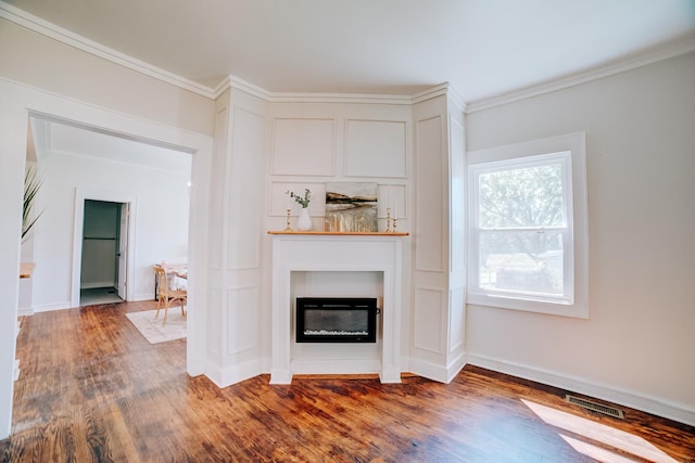 unfurnished living room featuring baseboards, visible vents, dark wood finished floors, a glass covered fireplace, and ornamental molding