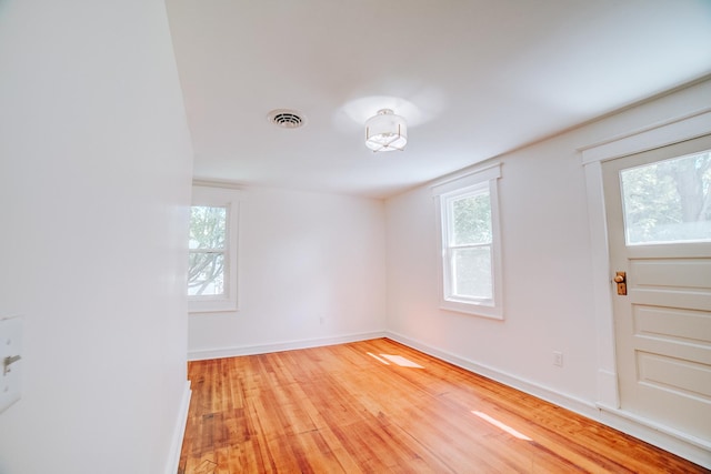 empty room with light wood-type flooring, baseboards, visible vents, and a wealth of natural light