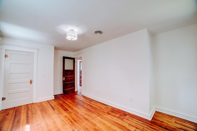 unfurnished room with light wood-style flooring, visible vents, and baseboards