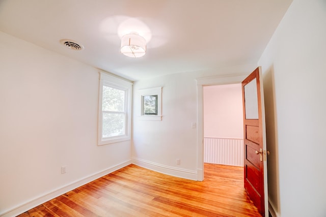 unfurnished room with light wood-type flooring, visible vents, and baseboards