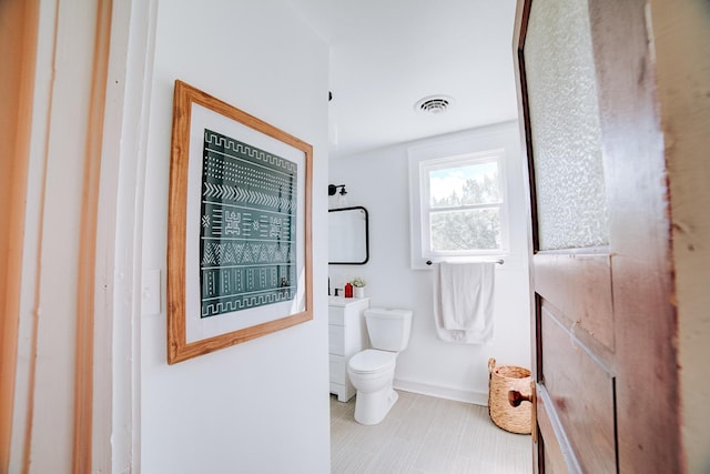 bathroom featuring toilet, baseboards, and visible vents