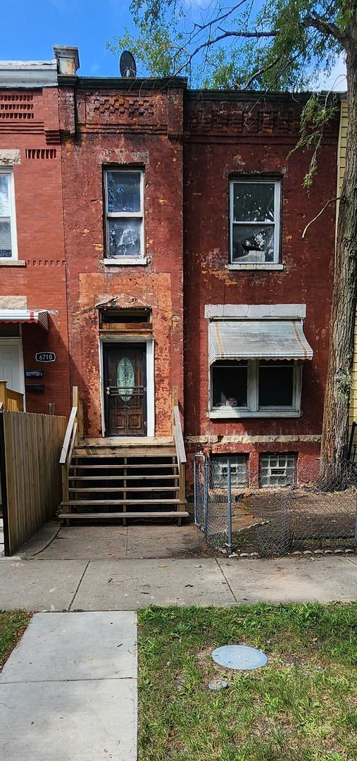 view of front of home featuring brick siding and fence