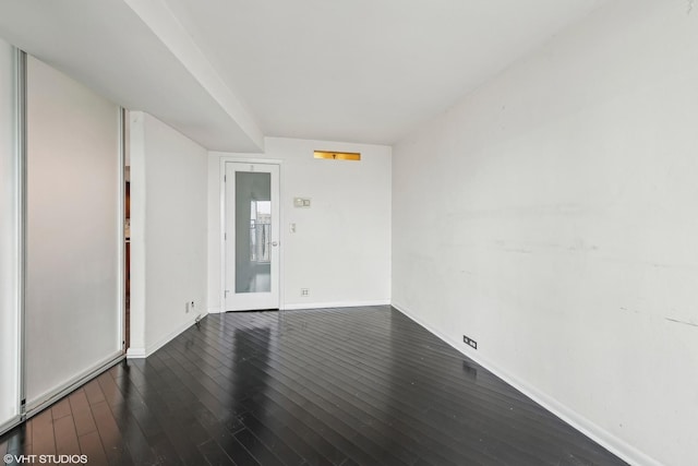 unfurnished room with dark wood-type flooring and baseboards