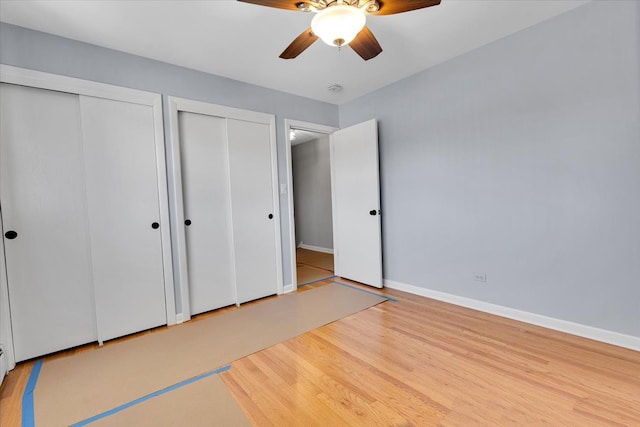 unfurnished bedroom with multiple closets, wood-type flooring, and ceiling fan