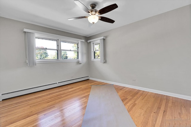 empty room featuring light hardwood / wood-style floors, a baseboard radiator, a wealth of natural light, and ceiling fan