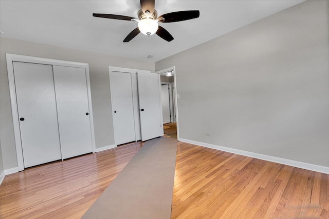 unfurnished bedroom featuring light hardwood / wood-style floors, two closets, and ceiling fan