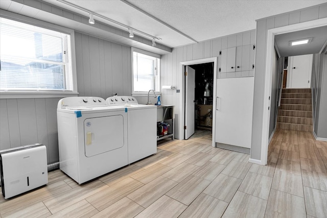 laundry area with a healthy amount of sunlight, a textured ceiling, washing machine and dryer, and rail lighting