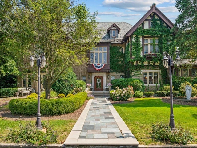 tudor home featuring a front lawn and brick siding