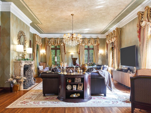 interior space with a raised ceiling, a fireplace with flush hearth, wood finished floors, crown molding, and a chandelier