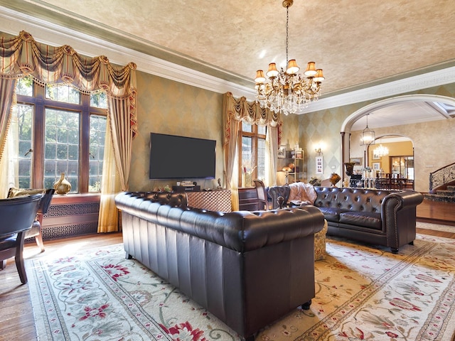 living room featuring a healthy amount of sunlight, arched walkways, a notable chandelier, and wood finished floors