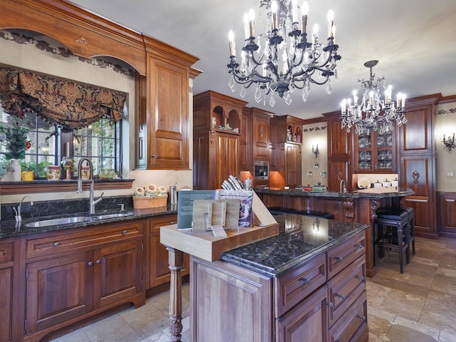 kitchen featuring a kitchen island, glass insert cabinets, an inviting chandelier, a kitchen bar, and a sink