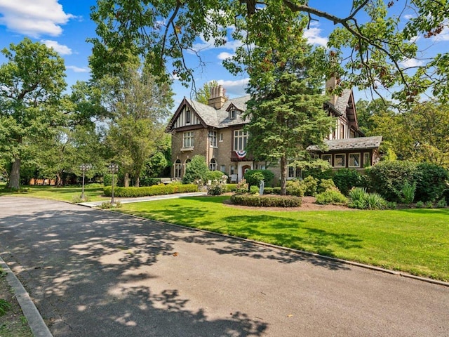 english style home with a front yard and a chimney