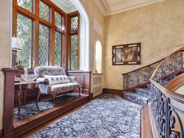 living area featuring a healthy amount of sunlight, crown molding, a towering ceiling, and baseboards