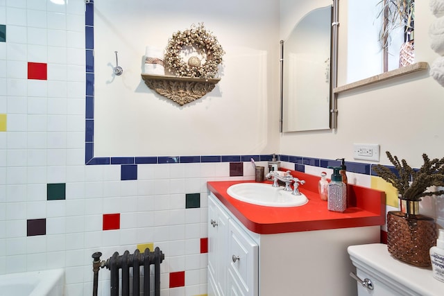 full bathroom with radiator, a wainscoted wall, toilet, vanity, and tile walls