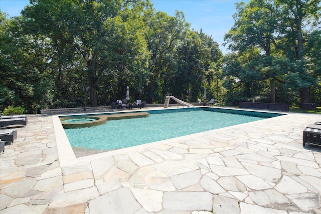 view of pool featuring a patio area, a pool with connected hot tub, and a water slide