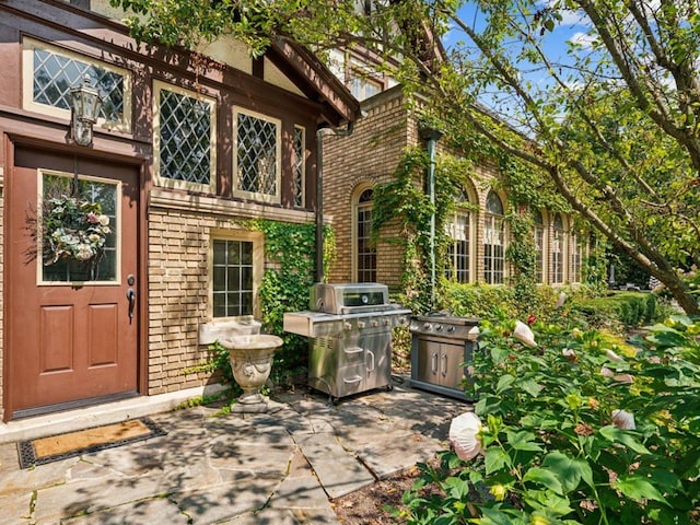 entrance to property featuring a patio and brick siding