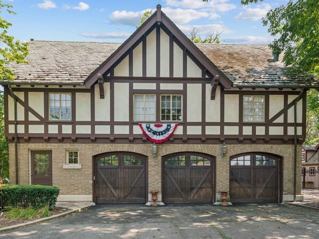 view of front of home with driveway, brick siding, an attached garage, and stucco siding