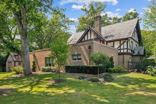 view of front of house with brick siding, a chimney, fence, a front lawn, and stucco siding