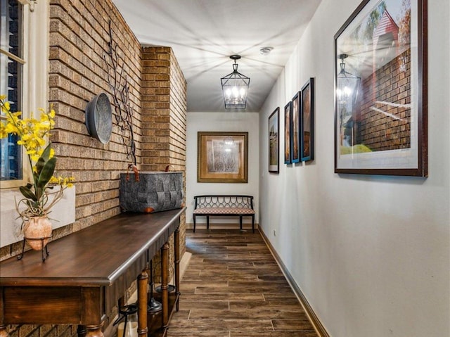 hallway with a chandelier, dark wood-type flooring, and baseboards