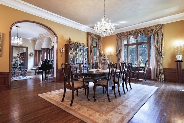 dining area with a chandelier, arched walkways, wood finished floors, and wainscoting