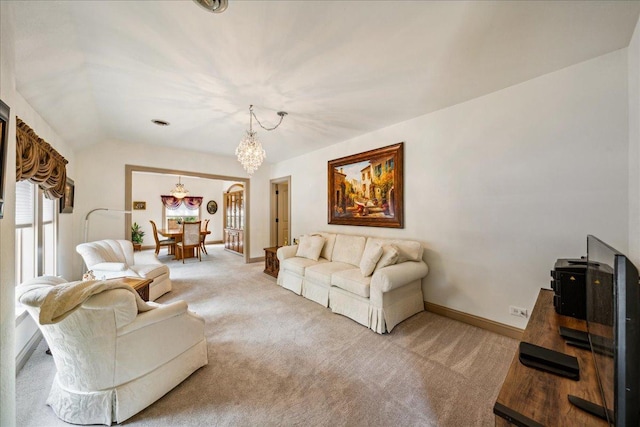 living area with vaulted ceiling, light carpet, a notable chandelier, and baseboards