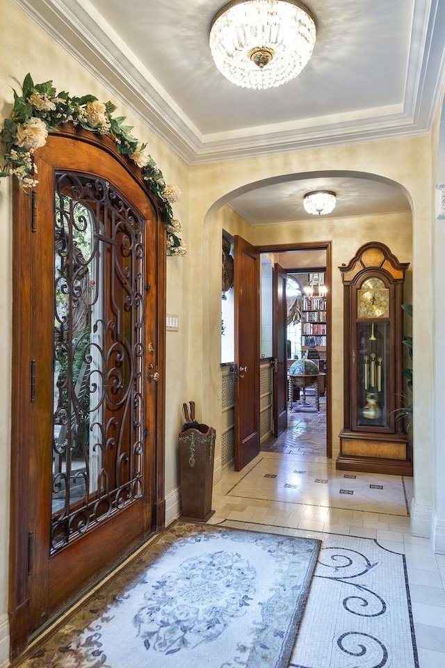 foyer entrance featuring baseboards, arched walkways, and crown molding